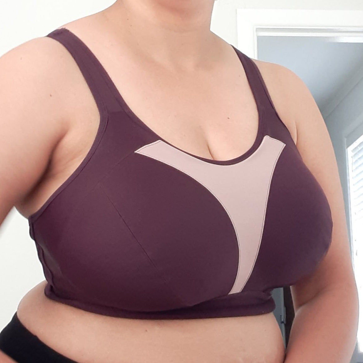 Person wearing a purple sports bra in a room with a window.