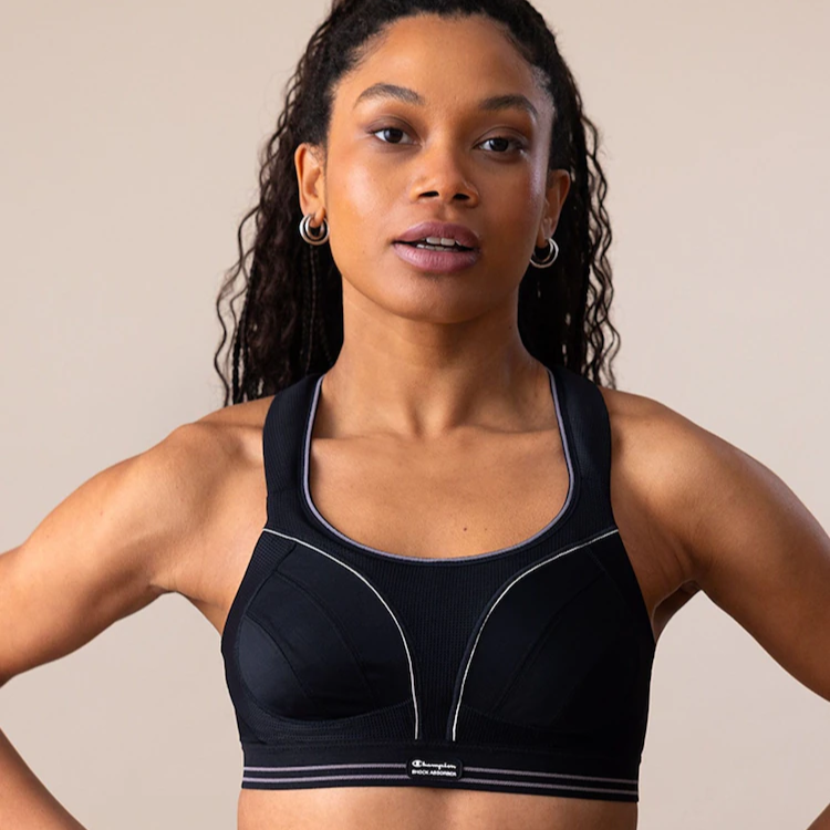 Woman wearing a black sports bra with a beige background
