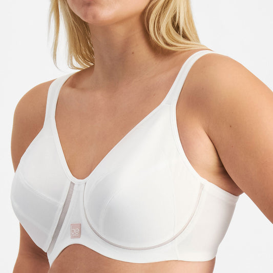 Woman wearing a white sports bra with a visible brand logo on a plain background