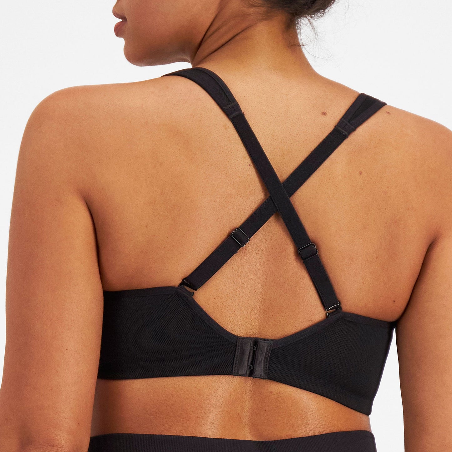 Black sports bra with criss-cross straps on a neutral background