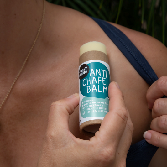 Person applying anti-chafe balm to their skin outdoors