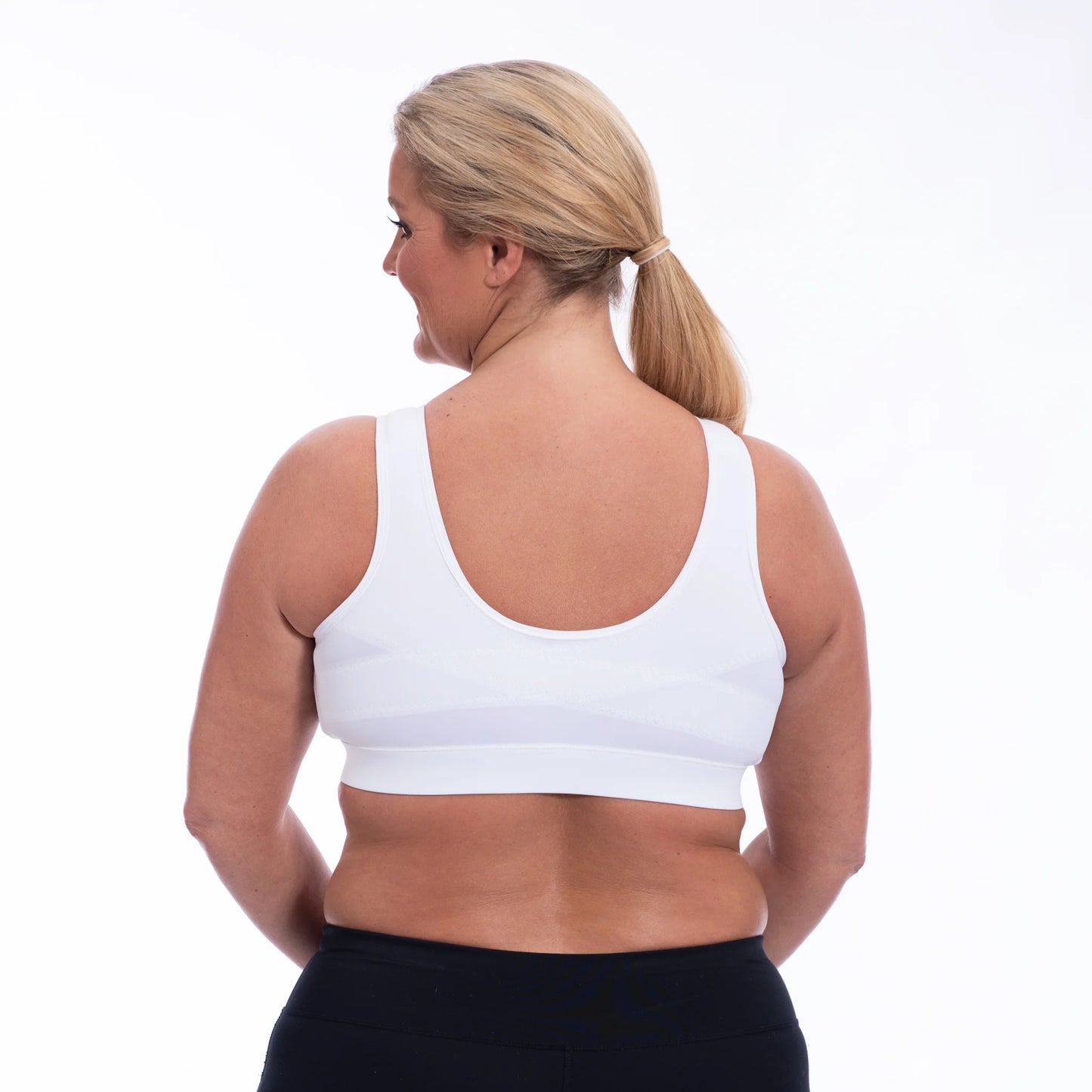 Curvy active woman wearing the Enell LITE in White showing the back support system